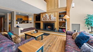 A spacious living area with a fireplace, wooden beams, a kitchen in the background, and a large window. - Ideal Location in Keystone; 10 min Walk to Lifts/Shops/Lake w/ Scenic Views (Keystone)
