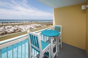 Ein Balkon mit Blick auf Strand und Meer, ein Pool und ein Tisch mit Stühlen.