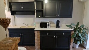A kitchen with dark cabinets, a microwave, and a coffee maker.