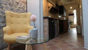 A living room with a yellow armchair, a glass table, and a vase with flowers.