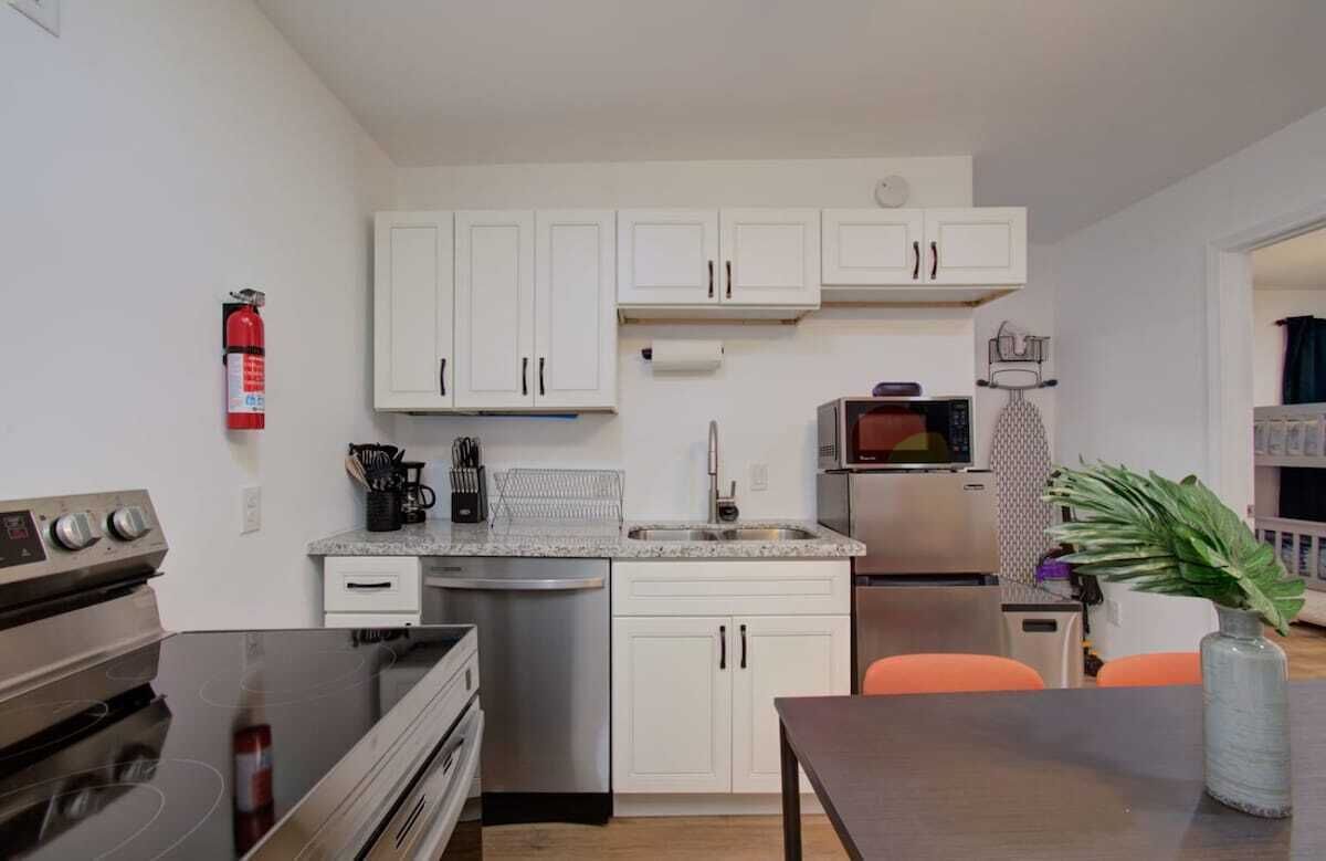 A compact kitchen with white cabinets, a stainless steel refrigerator, a microwave, and a coffee maker.
