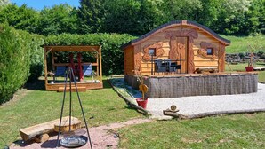 Una cabaña de madera con un columpio y una zona de barbacoa.