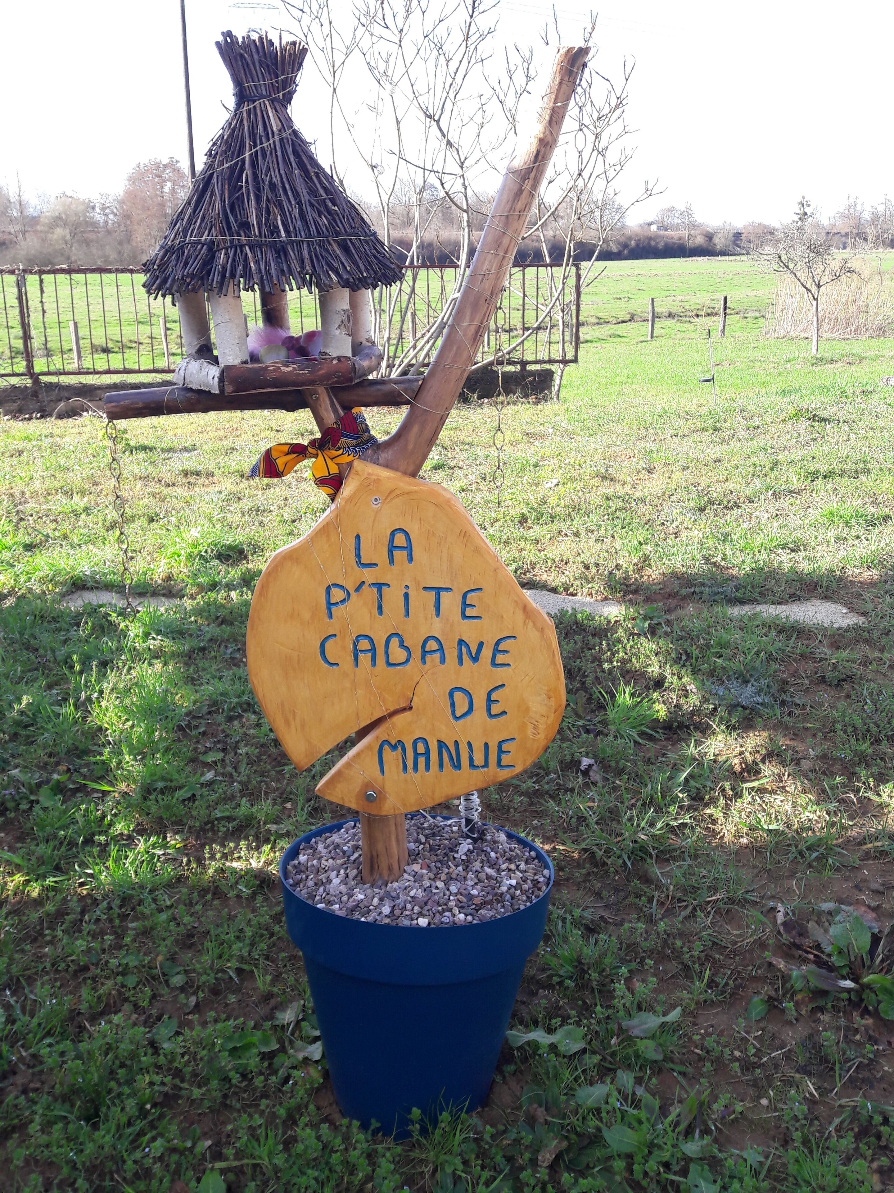 Een houten bord met tekst in een vreemde taal, geplaatst in een blauwe pot op het gras.