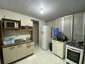 A compact kitchen with a microwave, refrigerator, sink, and stove. - Apto 2 quartos Centro de BC (Balneário Camboriú)