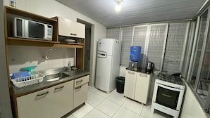 A compact kitchen with a microwave, sink, refrigerator, and a small stove. - Apto 2 quartos Centro de BC (Balneário Camboriú)