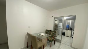 A small, modern kitchen with white cabinets, a refrigerator, and a water dispenser. - Apto 2 quartos Centro de BC (Balneário Camboriú)