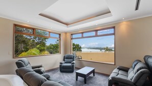 Una sala de estar moderna con un sofá, sillones, una mesita de centro y vistas a un balcón y un paisaje.