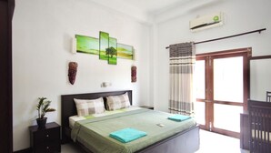 A bedroom with a bed, a potted plant, a red rug, a painting, and a window with curtains. - White House 101 (Galle)
