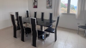 Een eetruimte met een zwarte tafel en stoelen, een kroonluchter en kunstwerken aan de muren.