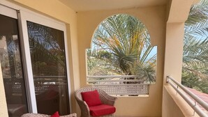 Een balkon met rieten meubilair en uitzicht op palmbomen.