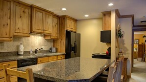 A kitchen with wooden cabinets, granite countertops, a built-in dishwasher, a refrigerator, and a microwave. - Canyons View 7: 2 Bedroom 2 bath vacation condo (Park City)