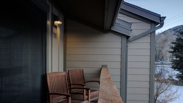 A porch with two wooden chairs and a stone fireplace. - Canyons View 7: 2 Bedroom 2 bath vacation condo (Park City)