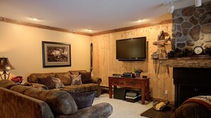 A cozy living room with a wooden wall, a flat-screen TV, a fireplace, and a comfortable sofa set. - Canyons View 7: 2 Bedroom 2 bath vacation condo (Park City)