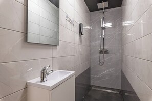 A modern bathroom with a white sink, a handheld showerhead, and a large mirror. - Wellness & Relax Apartment Lilly (Trebnje)