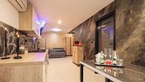 Una cocina moderna con salpicadero de mármol, armarios de madera y una zona de bar con vasos y botellas.