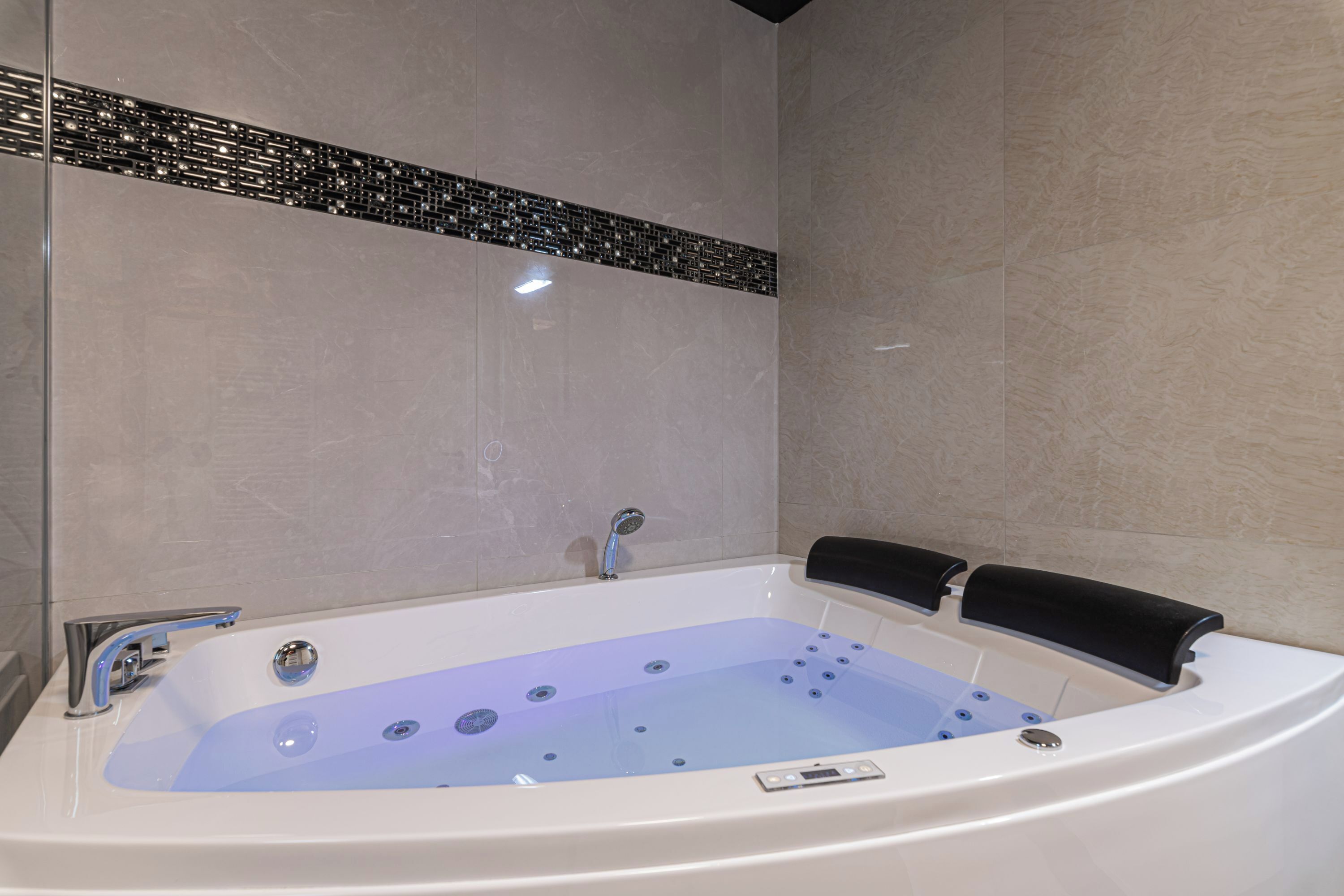 A modern bathroom with a large bathtub, a shower area, and a tiled wall.