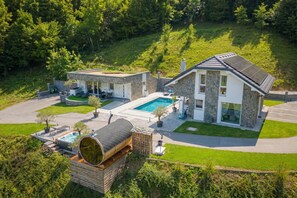 Ein modernes Haus mit Pool, Natursteinfassade und Holzterrasse.