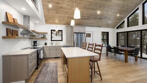 Une cuisine moderne avec des meubles en bois, un îlot central et un coin repas comprenant une grande table et des chaises.