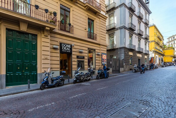 Une rue où sont garés des scooters et un bâtiment sur lequel on peut lire une pancarte indiquant « AFFAIRE CONCLUE ».
