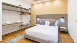 A modern bedroom with a large bed, built-in shelving, bedside tables, and a headboard with integrated lighting. - Colonna Apartment 4 by Wonderful Italy (Napoli)