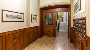 A hallway with wooden paneling, framed pictures on the walls, and a staircase in the background. - Colonna Apartment 4 by Wonderful Italy (Napoli)