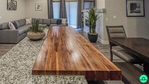 Un salon moderne avec une table à manger en bois, un canapé gris et des plantes en pot.