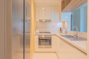 A modern kitchen with white cabinets, a stainless steel stove, and a built-in oven.