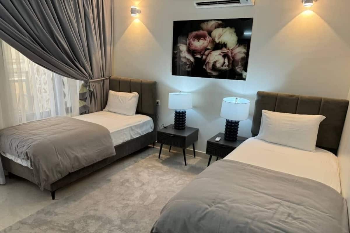 A hotel room with two beds, a large floral artwork on the wall, and two bedside lamps.