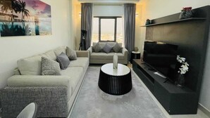 A modern living room with a sofa, a coffee table, a TV, and a ceiling fan. - WAAFI CITY CENTER RESIDENCE (Djibouti)