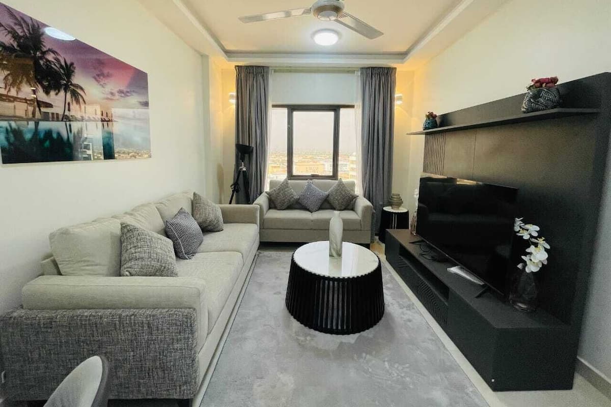 A modern living room with a sofa, a coffee table, a TV, and a ceiling fan.