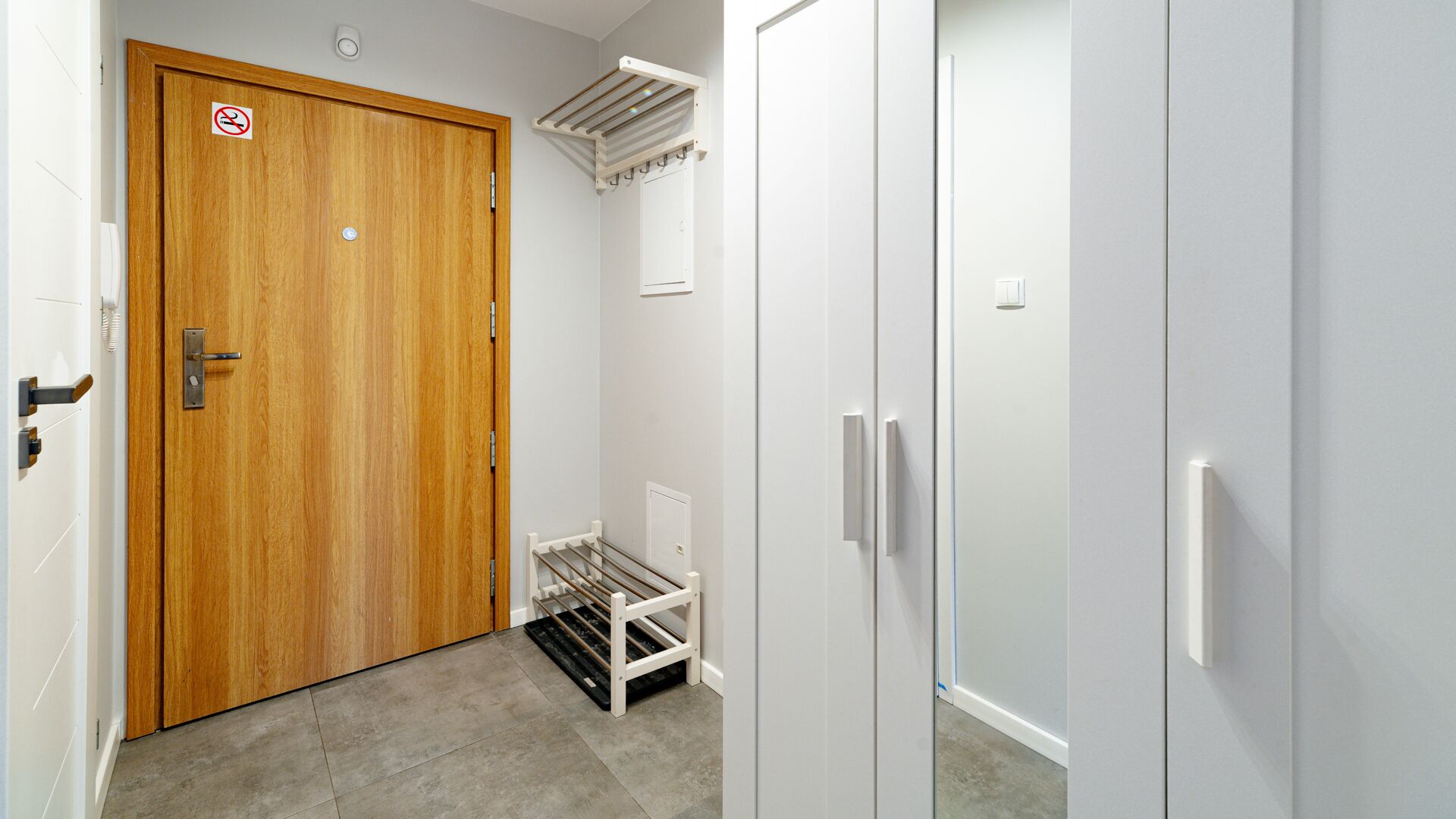 A hallway with a wooden door, a white radiator, and a white wardrobe.
