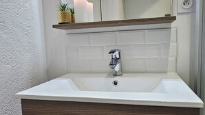 A bathroom with a white sink, wooden vanity, and a large mirror. - La Jungle - Vue Directe et Magnifique sur le Port (Saint-Valery-en-Caux)