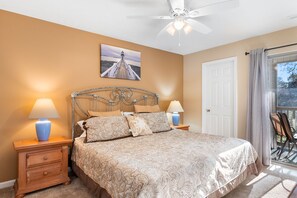 Classic bedroom with a large bed, nightstands, and a ceiling fan, offering a view of the outdoors.