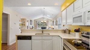 A modern kitchen with white cabinetry, a built-in dishwasher, a microwave, and an oven. - TB 19H Par tee Updated and spacious three bedroom condo in True Blue (Pawleys Island)