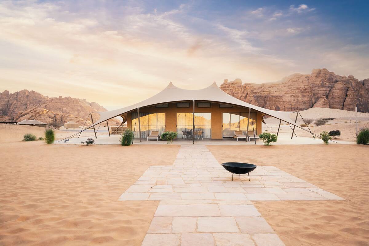 A desert resort with a large tent-like structure, a paved walkway, and a black bowl in the foreground.