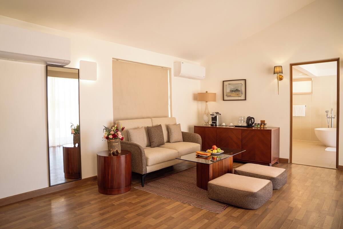 A modern living room with a sofa, ottomans, a coffee table, and a wooden cabinet.