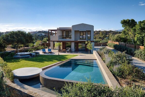 A modern two-story house with a swimming pool, outdoor seating, and a well-maintained garden.