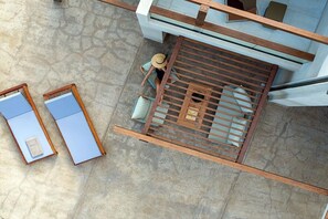 An aerial view of a modern building with a spacious patio area, a wooden deck, and a glass railing overlooking the interior. - Beachfront Linum Escape Retreat (Agios Nikolaos)