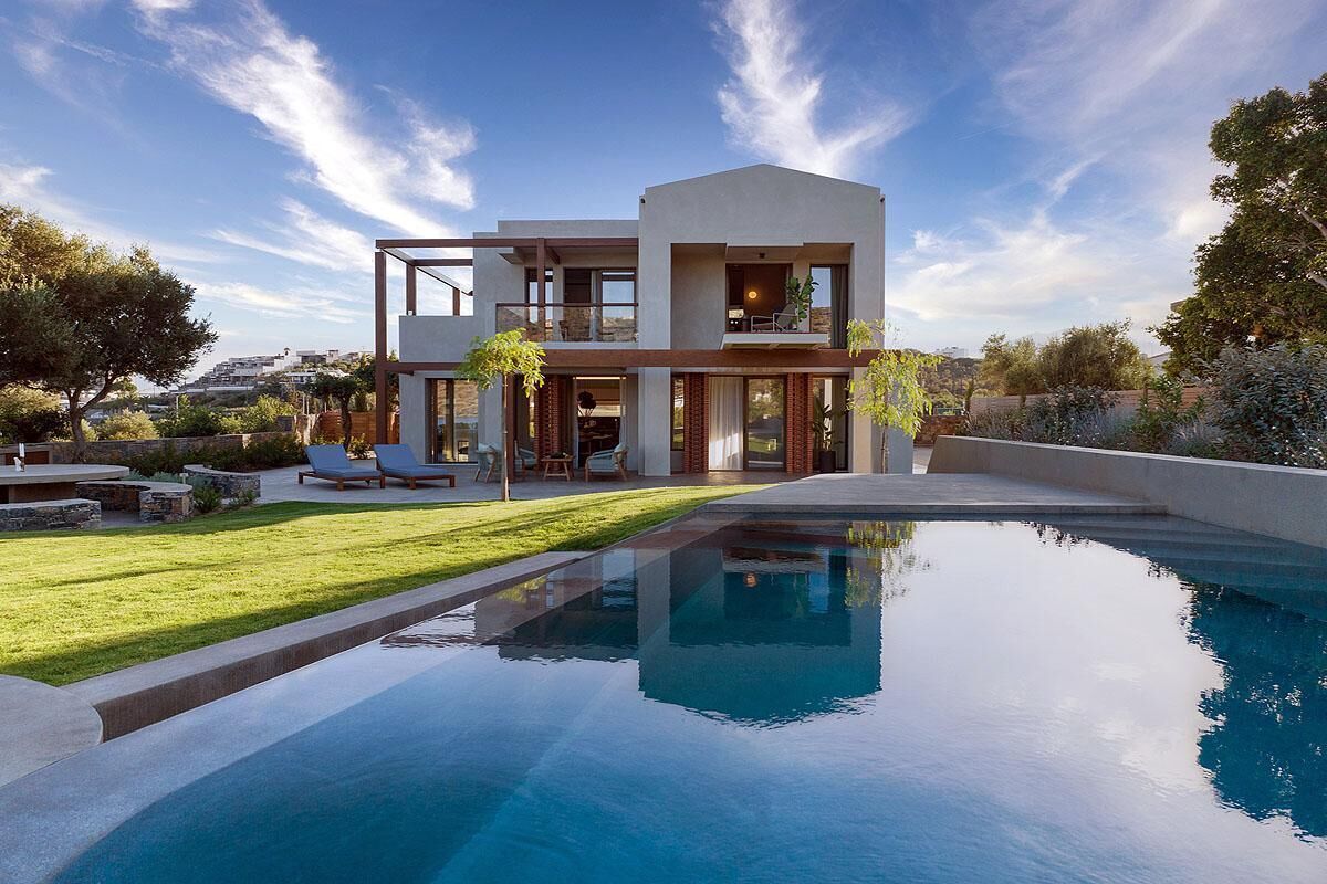 A modern two-story house with a swimming pool in the foreground.