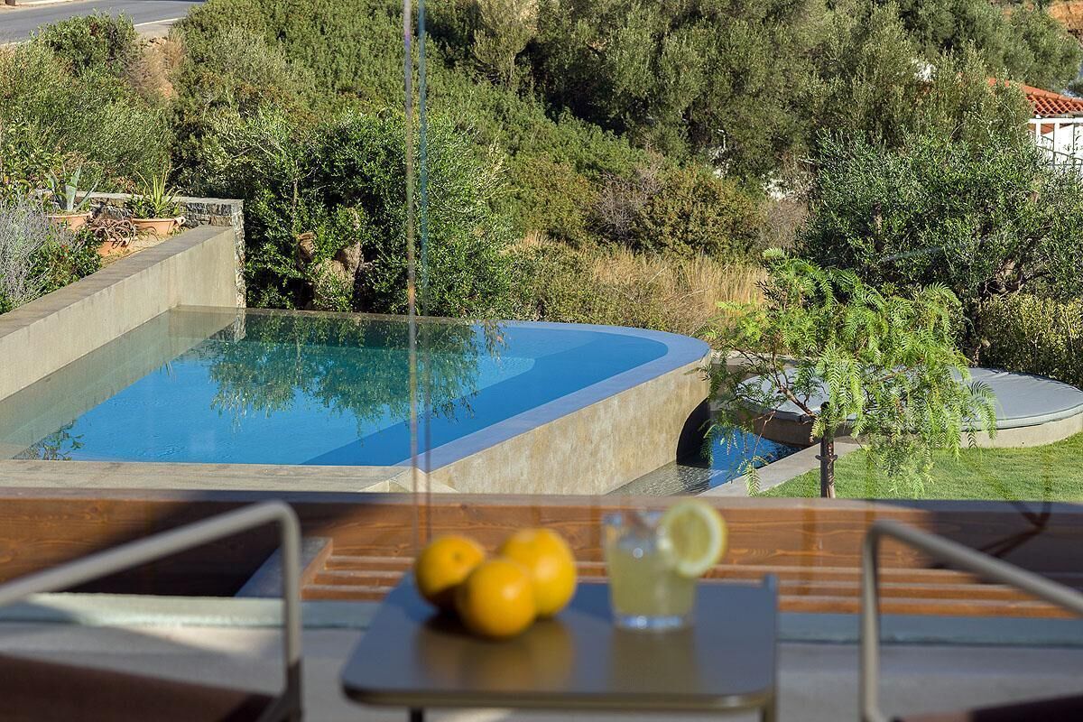 Una piscina con vistas despejadas del paisaje circundante, una mesa con limones y una bebida, y una silla.