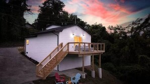 A small cabin with a wooden deck and outdoor seating area, surrounded by trees. - Summer Getaway!! Nearby attractions including Dollywood!! (Sevierville)