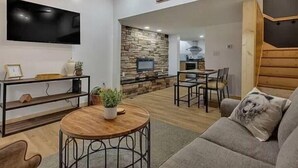 A modern living room with a stone fireplace, a flat-screen TV, and a cozy seating area. - Summer Getaway!! Nearby attractions including Dollywood!! (Sevierville)