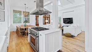 A spacious kitchen with a large island, wooden flooring, and a modern stove. - 5-Bedroom WaterColor Home | Breathtaking Gulf & Lake Views | Beach Steps Away (SANTA ROSA BEACH)