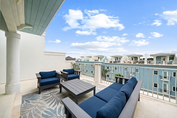 A balcony with outdoor seating, a pool, and a view of other buildings.