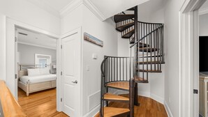 A bedroom with a bed, a white door, and a staircase with a black railing. - Coastal Daes | 4BR Townhome | Golf Cart Included | Santa Rosa Beach (Santa Rosa Beach)