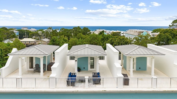 A coastal property with a white building, a covered porch, and a view of the ocean. - Coastal Daes | 4BR Townhome | Golf Cart Included | Santa Rosa Beach (Santa Rosa Beach)