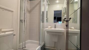 Un baño con ducha de mampara, inodoro, lavamanos y espejo.