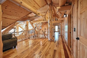 A spacious wooden interior with a high ceiling, a wooden staircase, and a sofa.