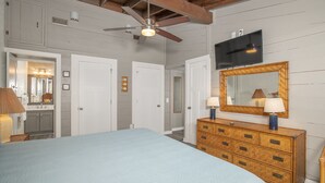 A bedroom with a bed, dresser, mirror, ceiling fan, and a television on the wall. - 4 BDR-Ocean Front Townhome in Pine Knoll Shores (Oceans 2) (Pine Knoll Shores)