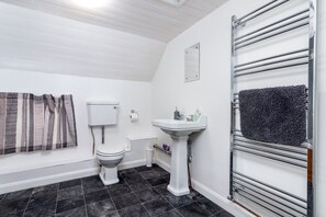A bathroom with a toilet, a pedestal sink, a towel rack, and a striped shower curtain.